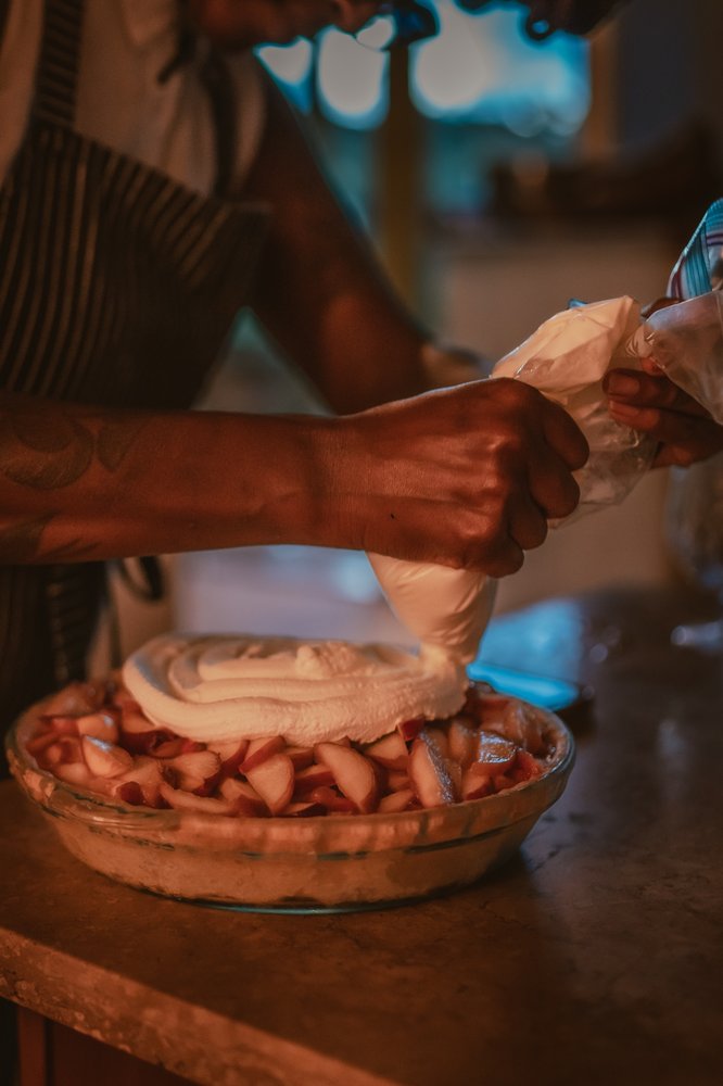 Hands piping cream onto a pie