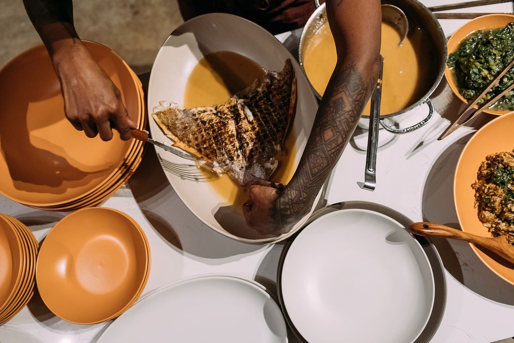 Overhead view of fish, greens, and stew at the service table